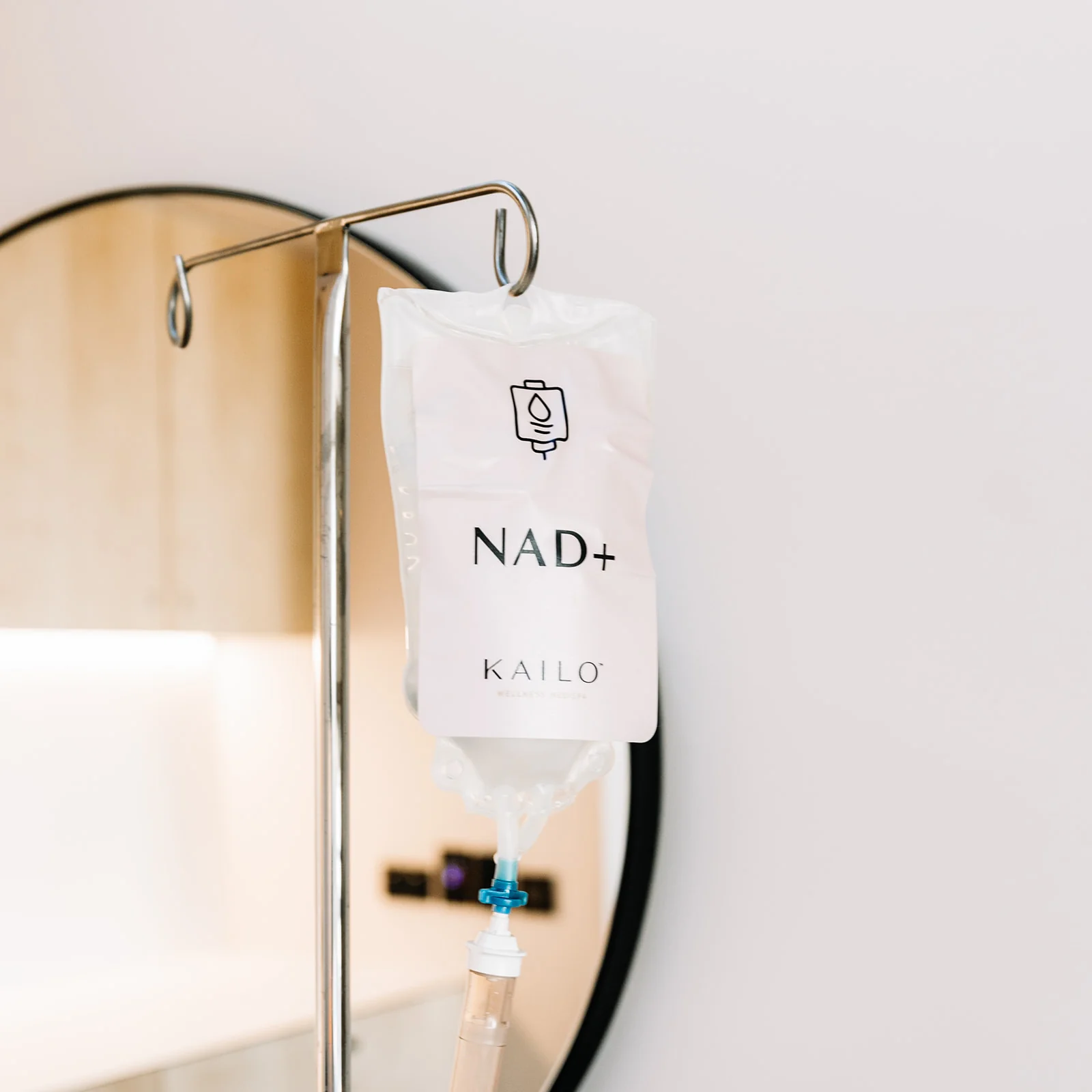 KAILO NAD+ IV bag hanging on a stand beside an arched mirror.